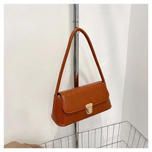 Vue détaillée de la texture crocodile marron et du fermoir doré sur le sac à bandoulière