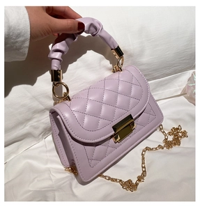 Detail of light purple quilted handbag featuring gold chain strap and pleated handle