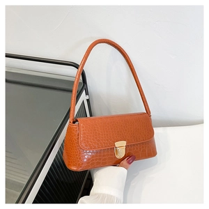 Détail de la texture crocodile orange et boucle dorée sur un sac à bandoulière chic