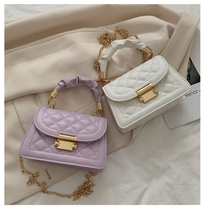 Detail of quilted mini crossbody bags in purple and white with ruffled handles and gold chains