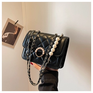 Detail view of the black quilted texture and elegant pearl buckle on the handbag
