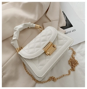 Detail of white quilted crossbody bag with golden clasp and pleated cloud handle
