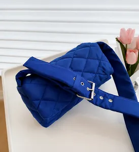 Détail du sac matelassé en nylon bleu avec large bandoulière et boucle en métal