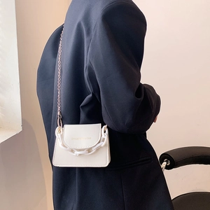 Mini cream white crossbody bag with resin chain and metal strap on black blazer
