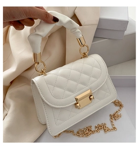 Detail of white quilted crossbody bag with soft scrunchie handle and gold chain strap