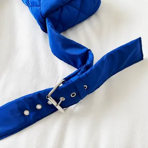 Gros plan sur la bandoulière matelassée bleue avec boucle de réglage en métal argenté