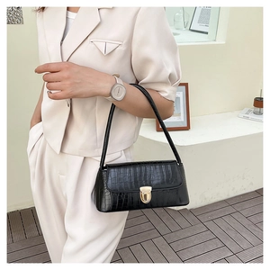 Gros plan du sac à bandoulière noir à motif crocodile et boucle dorée élégante
