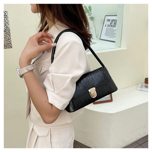 Détail du sac à bandoulière noir à motif crocodile avec fermoir doré sur modèle
