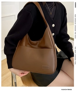 Detail of a brown leather Hobo bag featuring a front pocket and stylish logo tag
