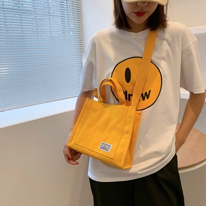 Minimalist vibrant yellow canvas crossbody handbag with top handle and brand patch
