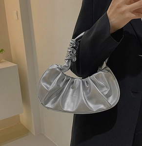 Close-up of silver pleated cloud bag featuring metallic texture and ruffled handle detail
