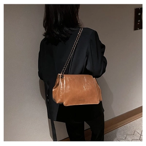 Brown oil-wax leather shoulder bag with gold chain strap shown on a model's back