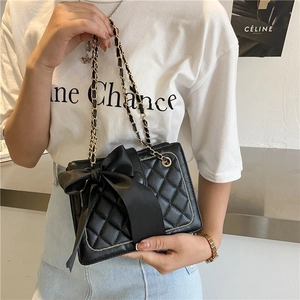 Elegante borsa trapuntata nera con fiocco in raso e tracolla a catena indossata da modella
