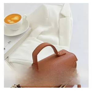 Detail of brown litchi pattern leather handbag with golden lock and sturdy curved handle