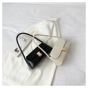 Détails de la texture effet pierre et boucle dorée sur les sacs baguette noir et crème