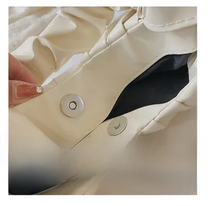 Detail view of the metal magnetic buckle and interior lining on a pleated cloud bag