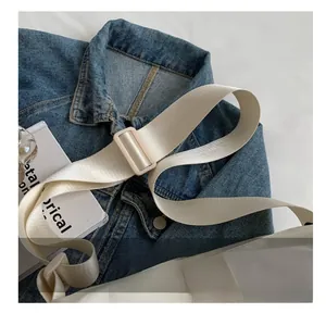 Detail of adjustable white nylon shoulder strap with matte buckle on casual tote bag