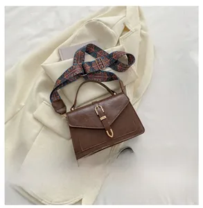 Close-up of brown leather crossbody bag featuring a colorful vintage woven shoulder strap