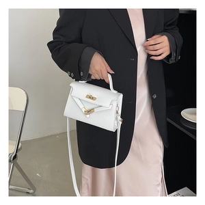 Mini white leather handbag with gold hardware shown on model in urban minimalist style