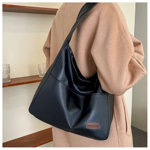 Detail view of large black matte PU leather tote bag with wide strap and side pocket