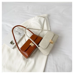Détail de sacs bandoulière aspect crocodile marron et beige avec fermoirs dorés