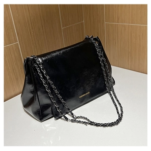 Detail of black glossy crinkled leather texture and metal chain strap on fashion bag