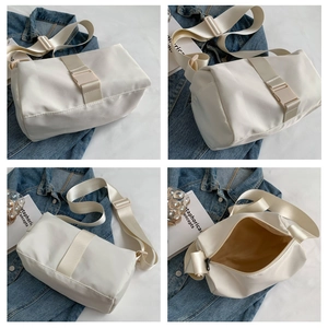 Detail view of white nylon cylinder crossbody bag showing wide strap and interior space