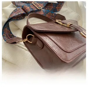 Detail of vintage brown messenger bag with wide colorful geometric pattern strap