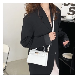 Detail of white mini Kelly bag with gold twist lock on stylish outfit background