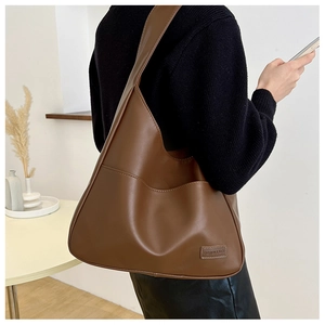 Detail view of large vintage brown PU leather tote with a side pocket and fashion label