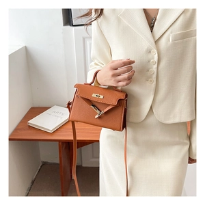 Detailed view of caramel brown leather handbag with gold metal clasp on a wooden table