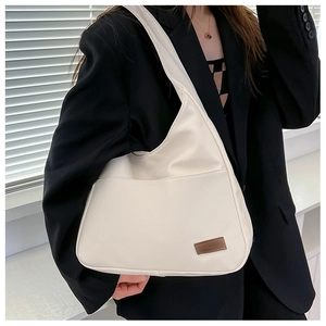 Detail of cream white faux leather tote bag showing side texture on a model