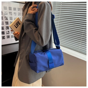 Detail of blue nylon crossbody bag featuring wide webbing straps and quick-release buckle