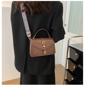 Detail of vintage brown square handbag with jacquard strap and gold buckle closure