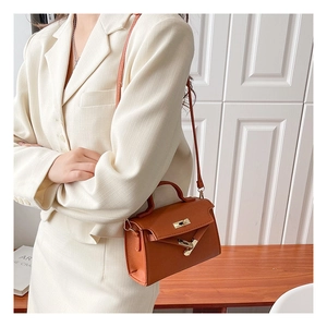 Brown lychee grain leather mini handbag with metallic lock and adjustable strap detail
