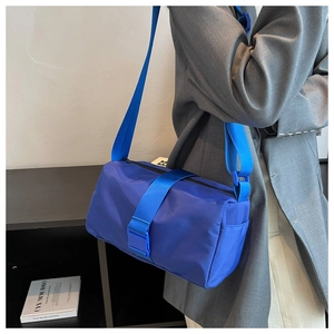 Detail of royal blue nylon crossbody bag with buckle strap on a grey suit jacket