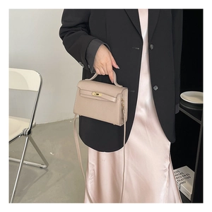 Classic apricot trapezoid handbag with gold rotary lock shown in a hand-carried style