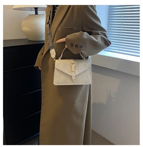 Detail of elegant beige crossbody bag with textured leather and bohemian woven strap