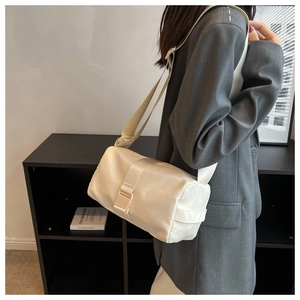 Detail view of cream oxford cross-body bag with plastic buckle closure on grey blazer
