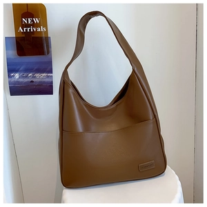 Detail of a brown faux leather hobo bag with stitched front pocket and fashion label