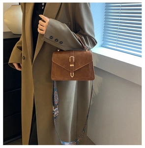 Detail of vintage brown shoulder bag featuring ethnic patterned wide strap and buckle