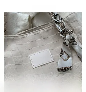 Close-up of woven texture tote bag with leather logo tag and silk scarf handle detail