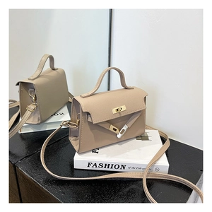Detailed close-up of beige crossbody bag with cross-grain texture and gold turn-lock closure