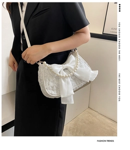 Dettaglio borsa bianca testurizzata con maxi fiocco in tulle e manico di perle eleganti