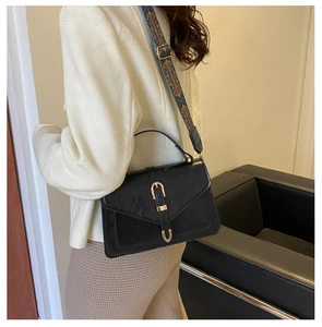 Detail of black vintage crossbody bag with golden buckle and bohemian embroidered strap