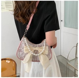 Dettaglio borsa jacquard rosa con manico di perle e fiocco in chiffon color crema