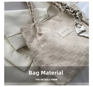 Detail of beige tote bag with textured fabric, woven handle and decorative scarf accessory