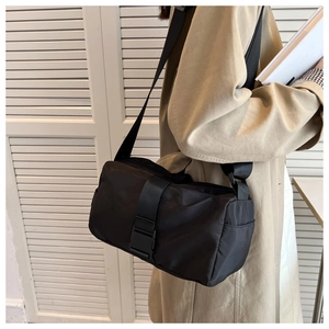 Detail of black nylon crossbody pillow bag with adjustable wide strap and buckle closure