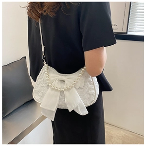 Dettaglio borsa a mano bianca con grande fiocco e manico in perle per uno stile unico