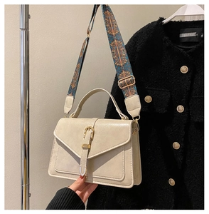 Detail of cream leather flap bag featuring ethnic style woven shoulder strap and gold buckle